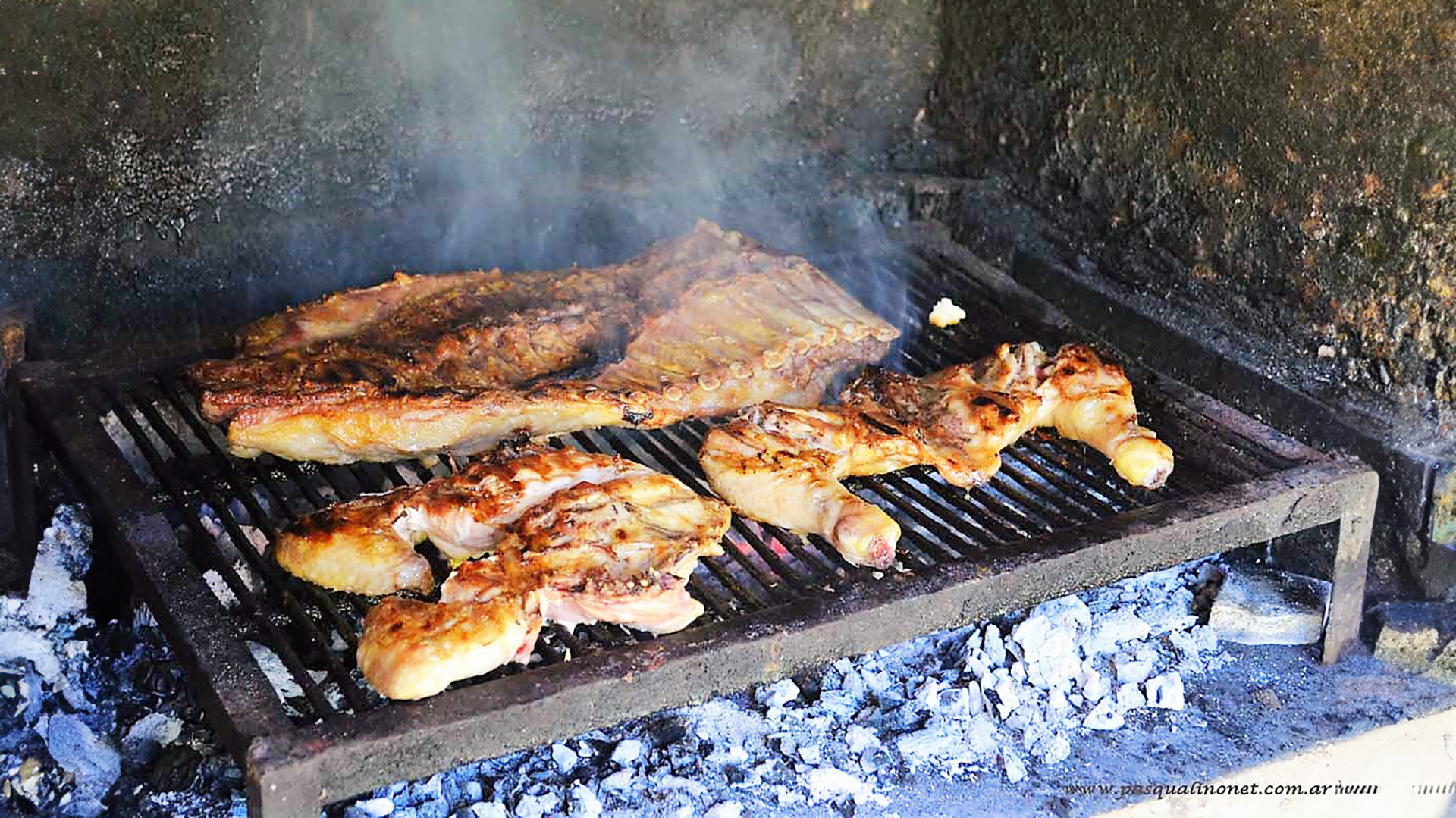 Cuatro grandes trozos de carne en un asador cocinar sobre un fuego